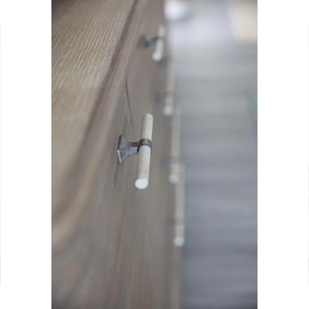 A close-up of a dresser drawer handle with a white and silver design.