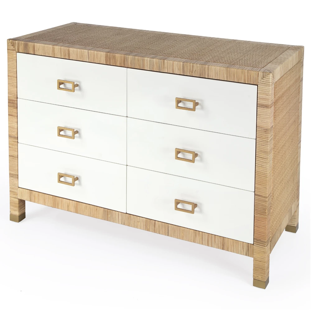 Dresser close-up showing white drawer fronts, brass handles, natural wood frame, woven texture on top and sides.