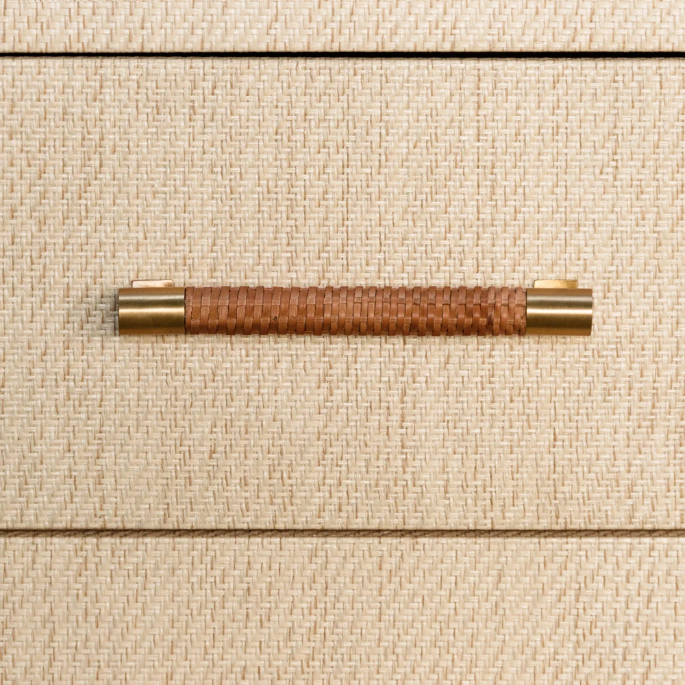 A close-up of a drawer handle on a beige dresser.