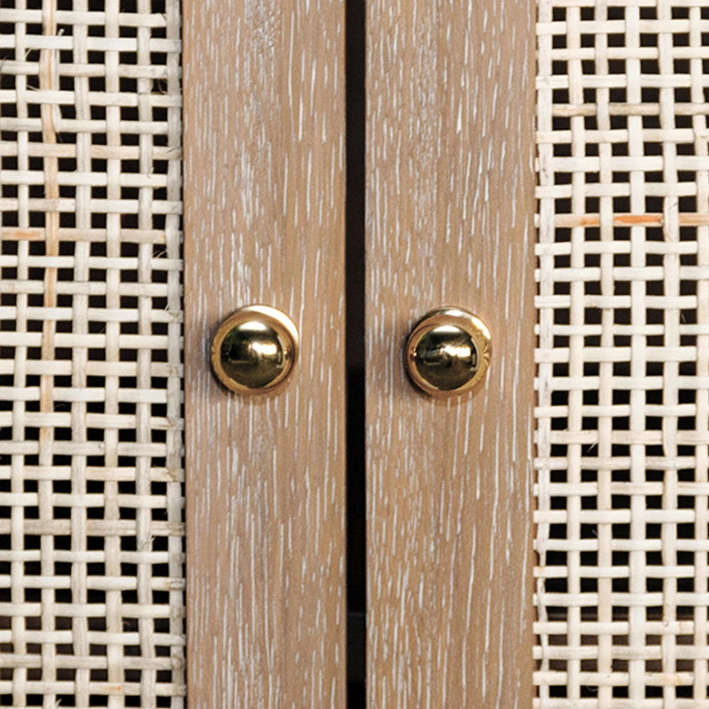 Close-up of gold knobs on light brown wooden cabinet with woven rattan panels.