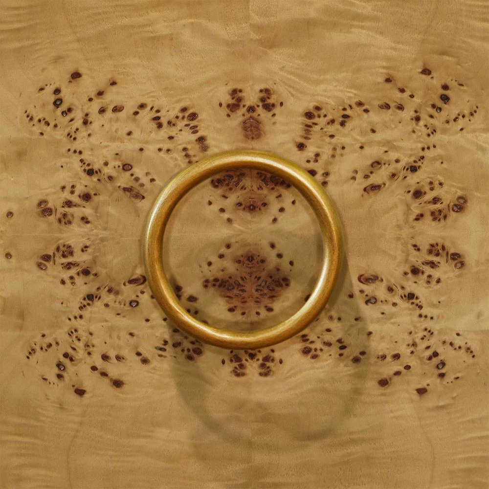 A close-up of a cabinet door handle on a wooden vanity.