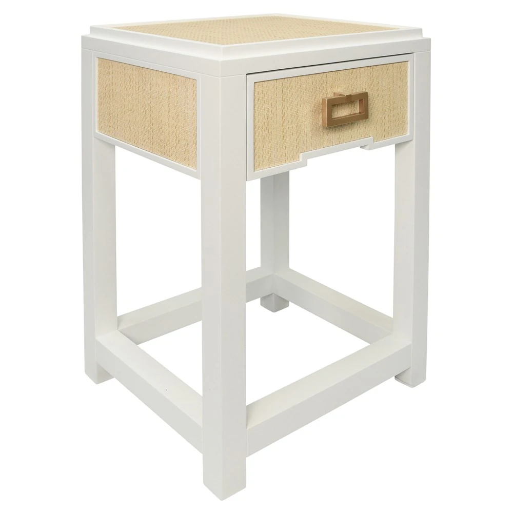 A white nightstand with a woven drawer and gold handle from an angle.