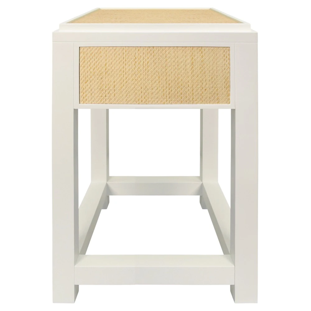A white nightstand with a woven drawer and gold handle from the front.