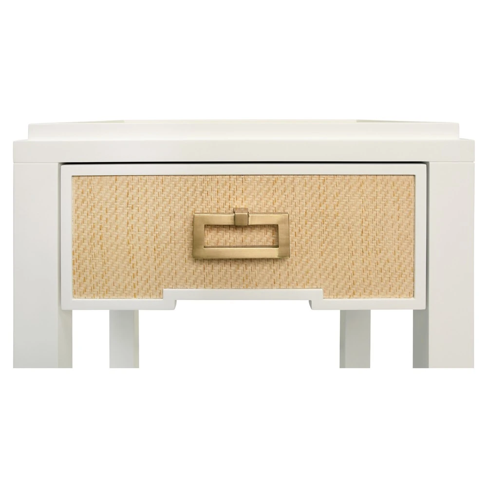 A close-up of the woven drawer and gold handle of a white nightstand.