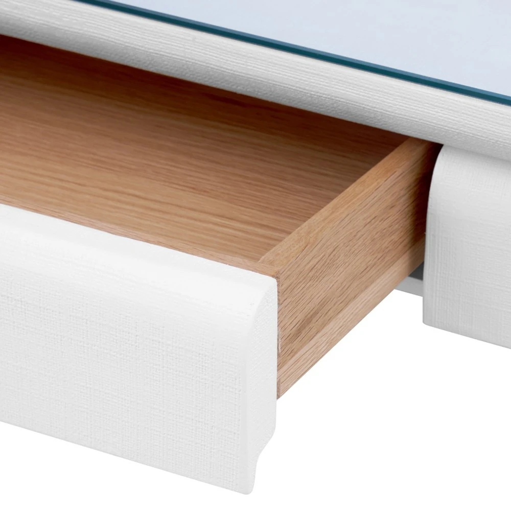 A close-up of an open drawer in a white table.