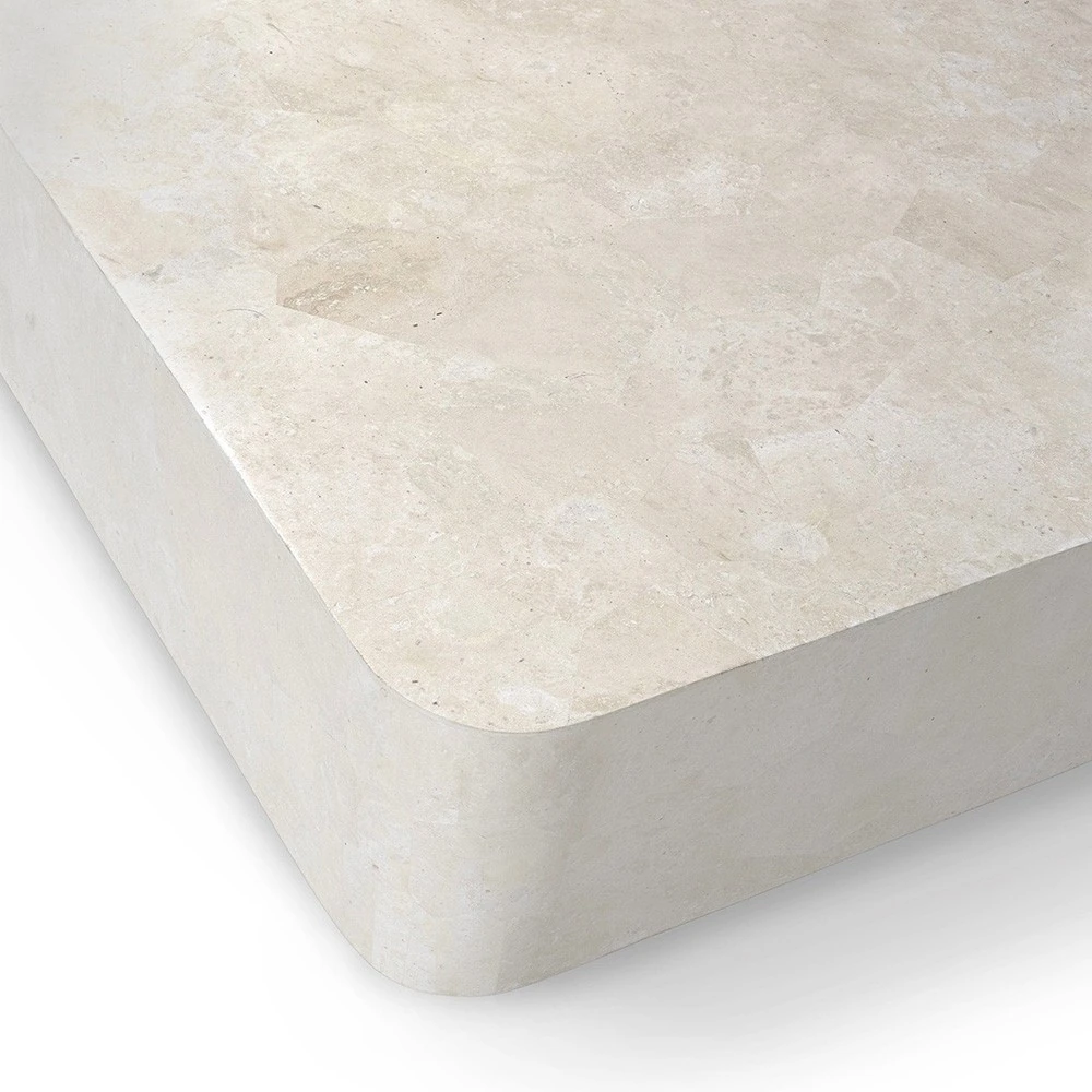 A close-up of the corner of a beige stone coffee table