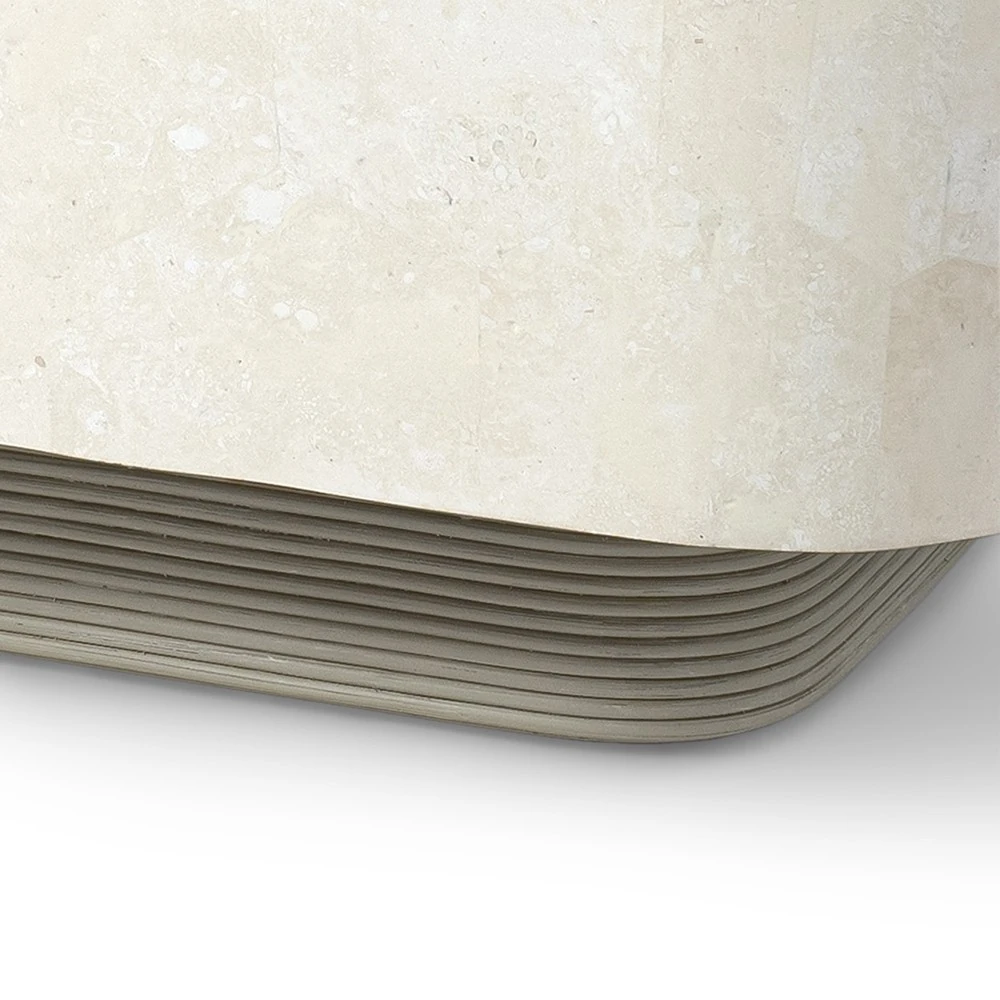 A close-up of the ribbed base of a beige stone coffee table