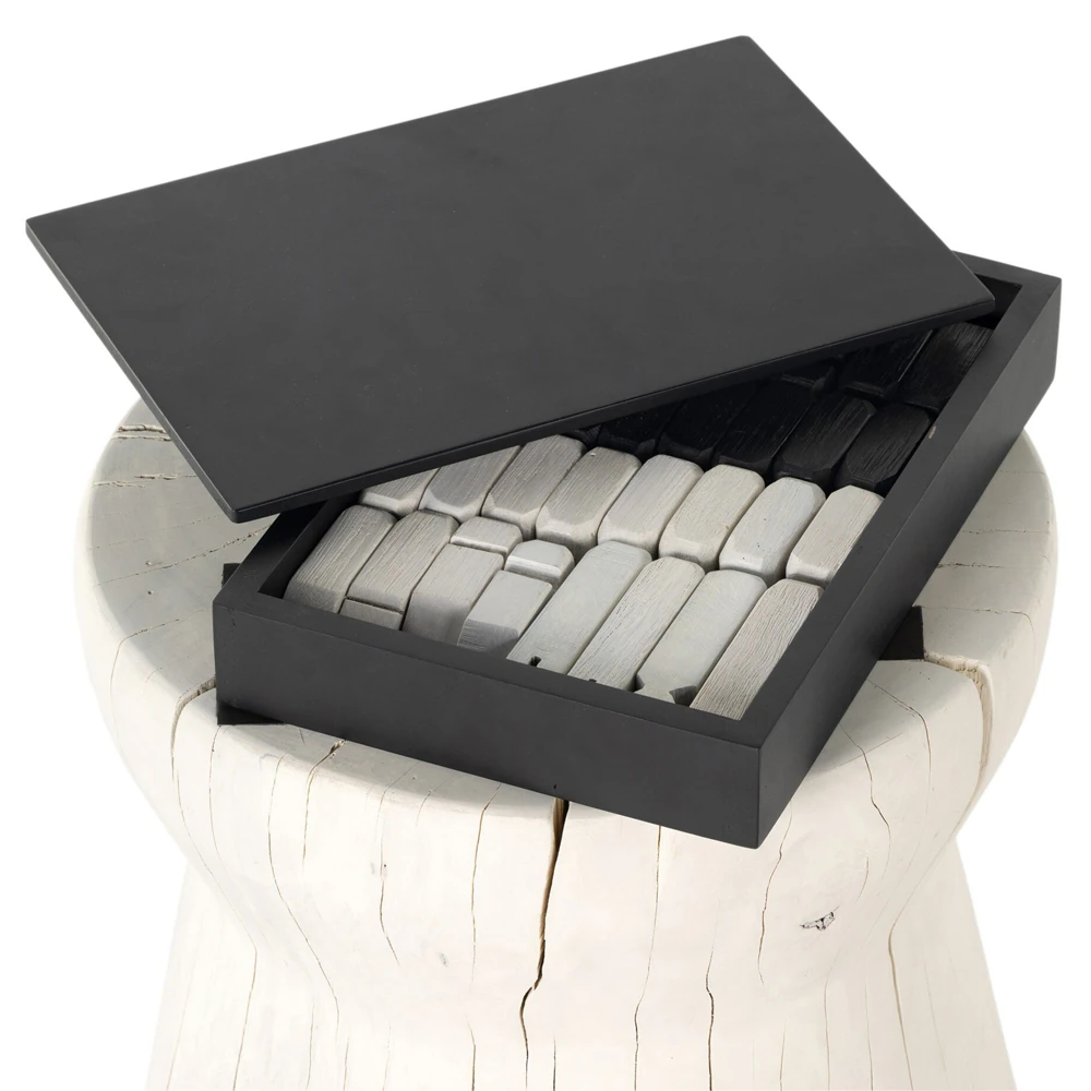 The chessboard top with black and gray tiles and the black and white figurines set on a sturdy stump base, decorative functional art piece.