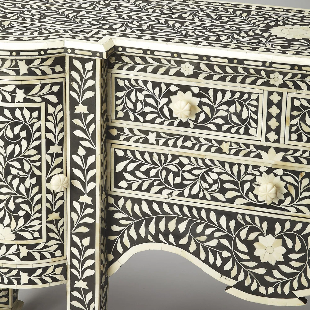 A close-up of a black and white desk with intricate floral designs on the drawers