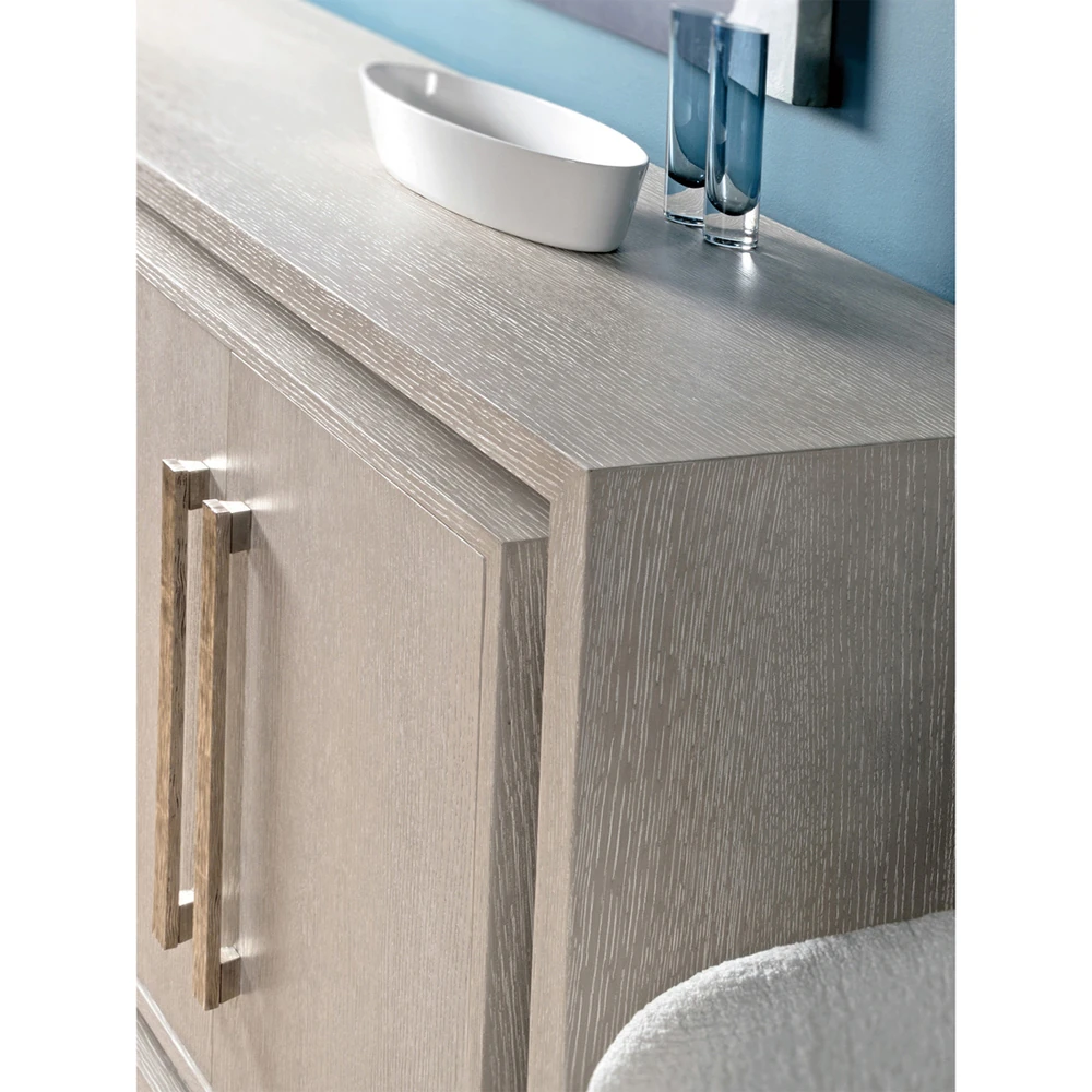 A close-up of a light gray cabinet with a bowl and glasses on top.