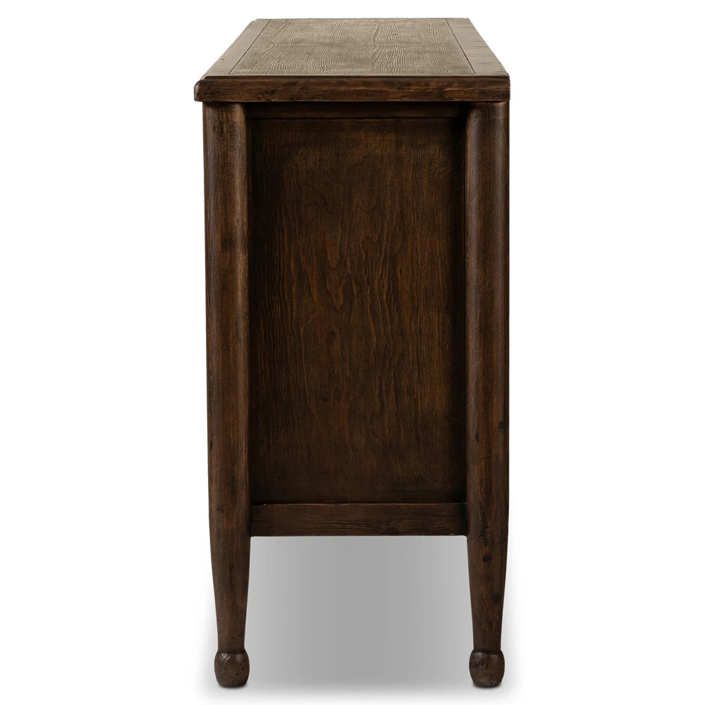 End view of solid wood sideboard with tapered legs and small bun feet in a dining room setting.