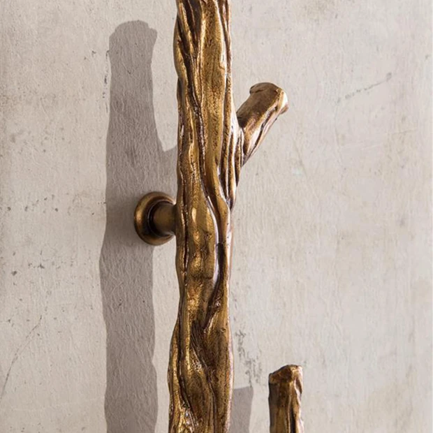 Close-up of the branch-like metallic handle with gold-bronze finish on the cabinet door