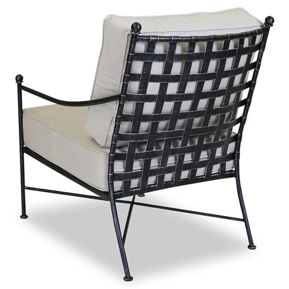 Two matching beige cushioned outdoor lounge chairs with metal lattice backs and a small side table setup on a patio.