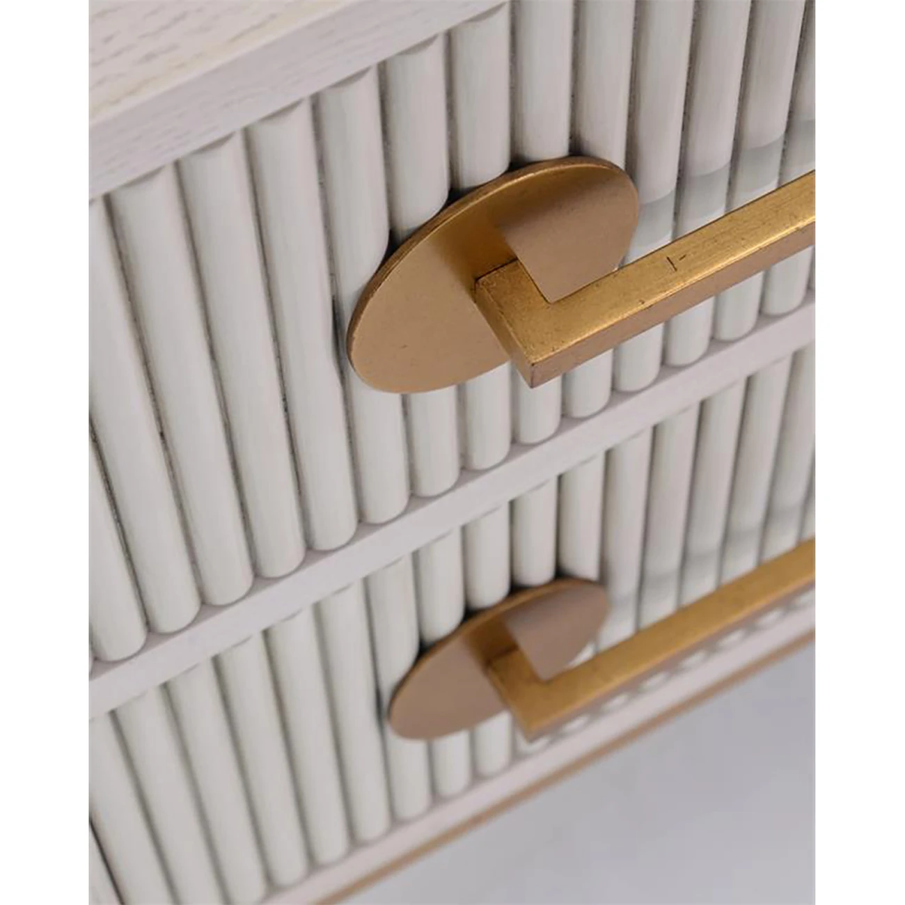 a close-up of a gold drawer handle on a white dresser