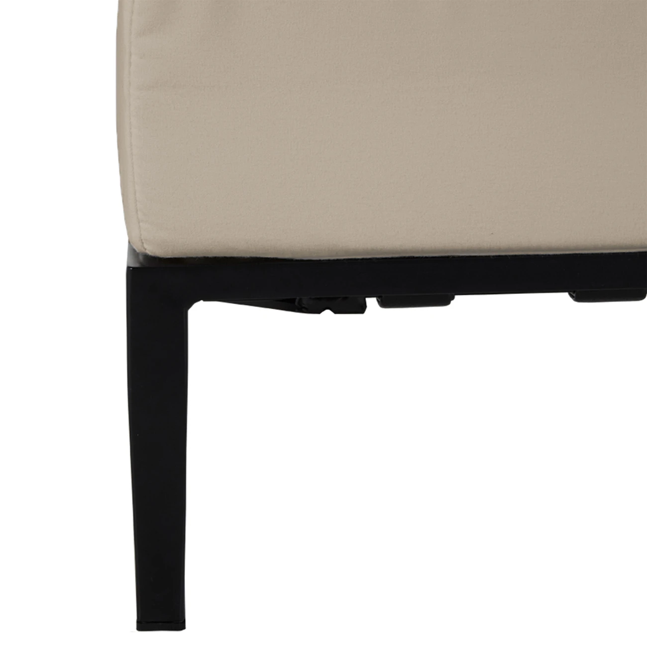 A close-up of the corner of a beige ottoman with a black metal base.